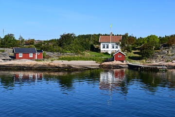 Reflection of traditional little red Scandinavian Swedish cabin on the shore of the Koster island