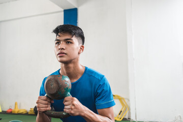 An asian man of intermediate fitness level does a set of goblet squats. Leg workout or cross training at the gym.
