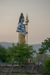A huge statue of lord Shiva holding a large trident in his hand with backdrop of lower himalayan mountain range. India. Shot captured during a trip to Haridwar in Uttarakhand, India.