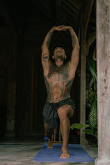 Young latin american tattooed man practice yoga outdoors during retreat vacation in Bali, stretching, meditation, wellness