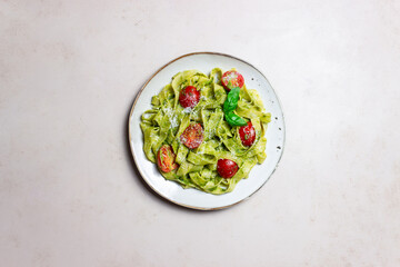 Linguini pasta with pesto sauce, tomatoes and cheese. Healthy eating. Vegetarian food. Italian cuisine.