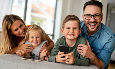 Happy young family having fun time at home. Parents with children using tablet