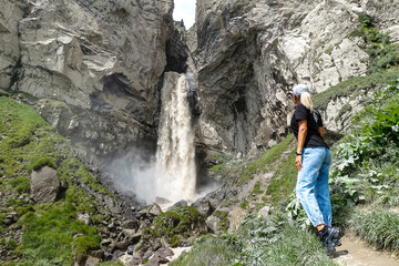 A girl at the Sultan-su waterfall surrounded by the Caucasus Mountains near Elbrus, Jily-su, Russia