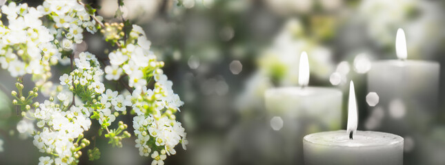 white flowering branch and 3 white candle lights outside in a garden, floral concept with burning...