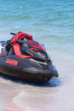 A red and black Sea Doo Jet ski parked on the sand at the waters edge at the beach, Brighton-Le-Sands