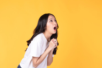 Image of feeling excited, shock, surprise and happy. Young asian woman standing on yellow background. Female face expressions and emotions body language concept. - obrazy, fototapety, plakaty