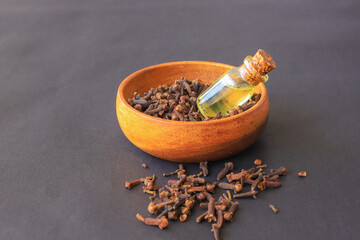 spice clove essential oil in glass bottle and dry cloves on dark wooden background