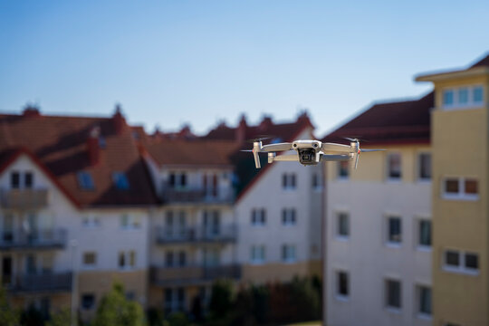Dron w mieście, dron leci wsród bloków mieszkalnych.