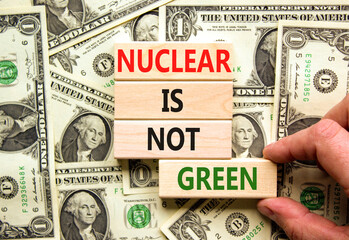 Nuclear is not green symbol. Concept words Nuclear is not green on wooden blocks. Businessman hand. Beautiful background from dollar bills. Nuclear is not green business concept. Copy space.