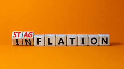 Stagflation or inflation symbol. Turned wooden cubes and changed the concept word inflation to stagflation. Beautiful orange background, copy space. Business stagflation or inflation concept.