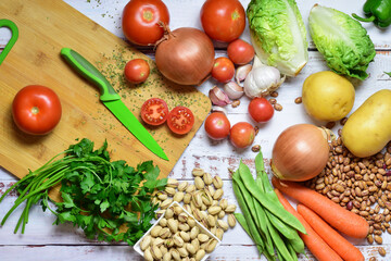 Assortment of healthy foods, vegetables, legumes, pistachios, on rustic white wooden boards. Aerial view.