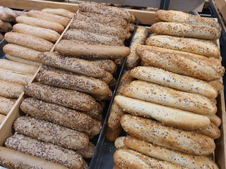 Variety of different types of French baguettes with brown and gold flax grain seeds in bakery or grocery store. Freshly baked bread