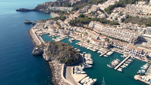 Aerial perspective of La Hedrradura city - Malaga Spain. Beautiful coastal city situated in south of Spain. View of the port and luxury urbanisation on hills. Mountains in background. Tilt up forward 