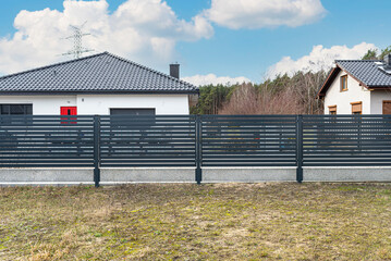 Modern anthracite panel fencing, visible spans and a fence foundation connector, view from the garden.