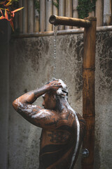 Shirtless muscular latin american male with tattoos standing taking shower outdoors after workout...