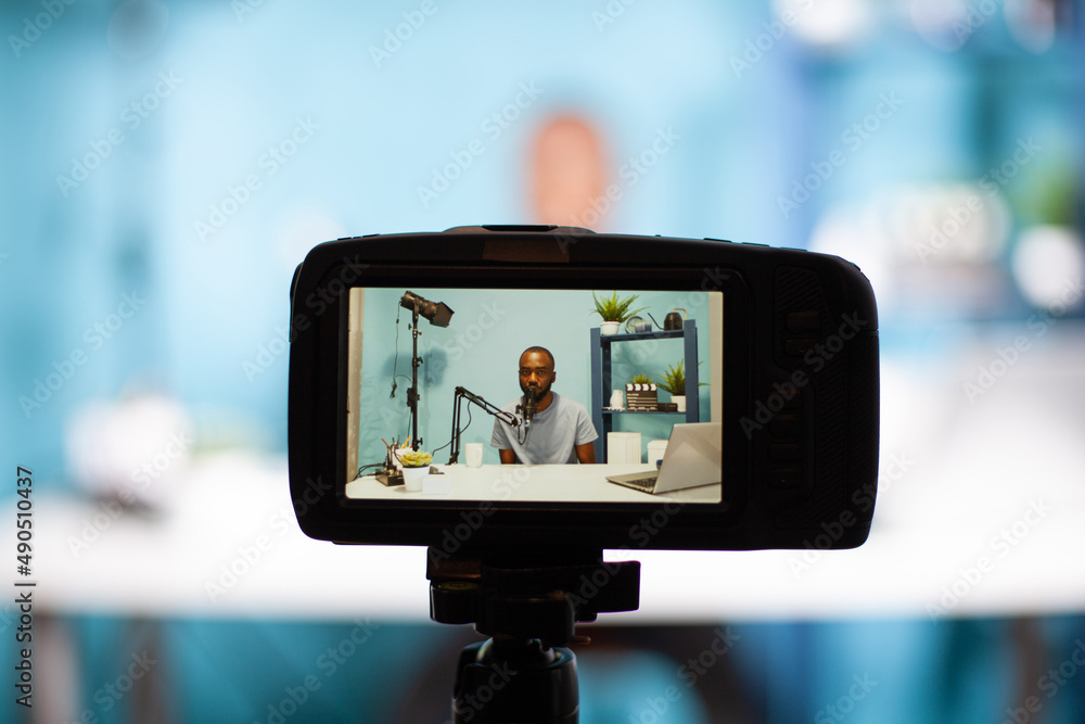 Poster closeup of professional digital camera on tripod recording vlogger talking at professional microphon