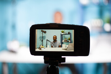 Closeup of professional digital camera on tripod recording vlogger talking at professional...