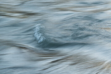 Silky water surface detail from rapid mountain stream in long exposure - abstract landscape