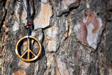 Handmade peace sign necklace against a tree trunk