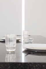 glasses and plates stand on a stone table top