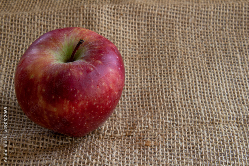 Poster red apple on burlap background with copy space.