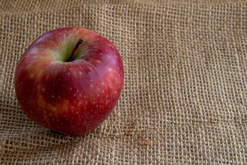 Red apple on burlap background with copy space.