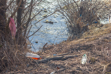 Garbage plastic bottles and plastic bags on the river bank, nature pollution, environmental disaster, selective focus