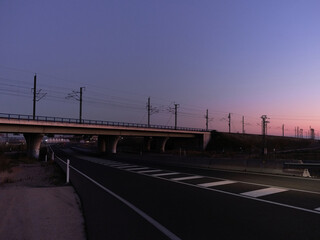 Railway bridge crossing a motorway at sunset
