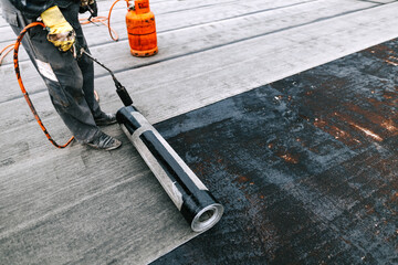 Workers installing bituminous membrane waterproofing system insulation with blowtorch