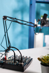Professional audio mixer used for recording audio podcast on desk in empty vlog studio with swivel mount boom arm microphone. Digital console equilizer used to broadcast live stream.