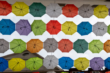 Kolorowe parasole rozwieszone nad ulicą, poddasze z okrągłym oknem.