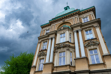 Fototapeta na wymiar Bogato zdobiona fasada kamienicy w Bielsku-Białej, kolumny, okna i pochmurne niebo.