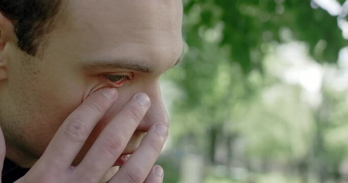 Sad young man cries on the cemetery. Funeral and farewell, honoring the passed relatives, 4k 60p Prores