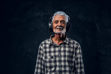 Contemporary grandpa with headphones dressed in plaid shirt