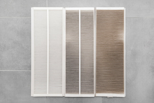 Dirty G4 filters and clean F7 filter from domestic mechanical ventilation with heat recovery, lying on gray ceramic plates.