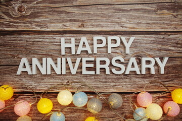 Happy Anniversary text with LED cotton balls decoration on wooden background