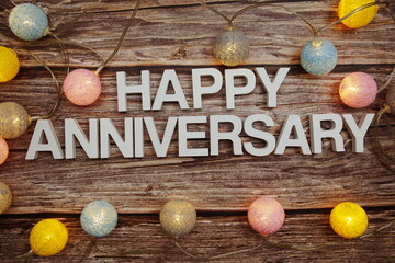 Happy Anniversary text with LED cotton balls decoration on wooden background