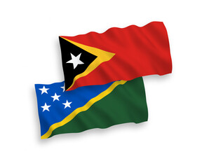 National vector fabric wave flags of Solomon Islands and East Timor isolated on white background. 1 to 2 proportion.