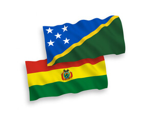 National vector fabric wave flags of Solomon Islands and Bolivia isolated on white background. 1 to 2 proportion.