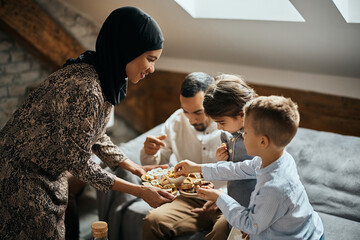 Happy Muslim mother serves dessert to her husband and kids at home.