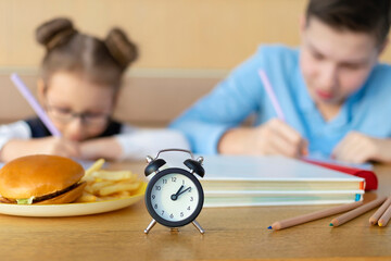 schoolchildren doing homework, studing at school. boy and girl waiting for lunch break at school. improper unhealthy diet of children. fast food kids
