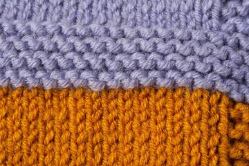 Knitted texture background. Hand-knitted wool. Macrophotography of a thread drawing. Orange-lilac texture of sweaters, pullovers, cardigans. Abstract natural background. Comfort autumn warmth concept