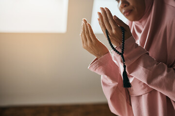 Close up of Muslim woman raises her hands into the position of making dua during a prayer.