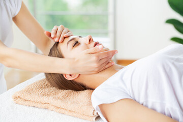 Fototapeta na wymiar Young woman enjoying of facial massage in spa salon