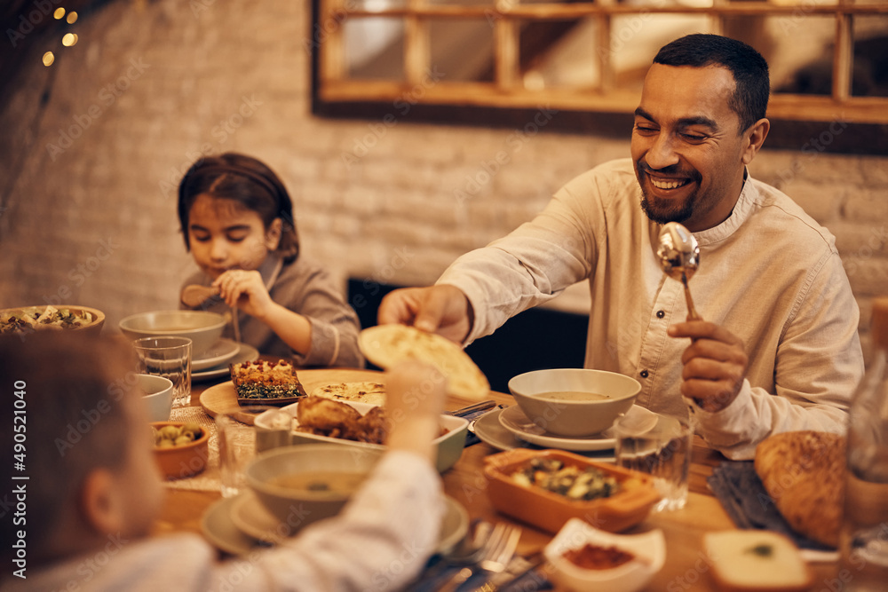 Poster happy muslim father gives his son lafah bread during dinner at dining table on ramadan.