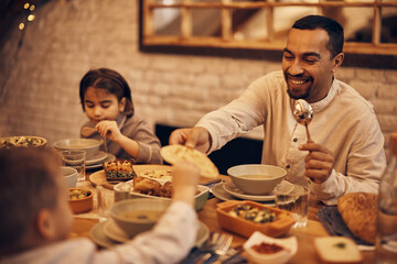 Happy Muslim father gives his son Lafah Bread during dinner at dining table on Ramadan.