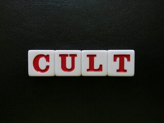 The word Cult is spelled with white and red tiles on a black leather background sheet