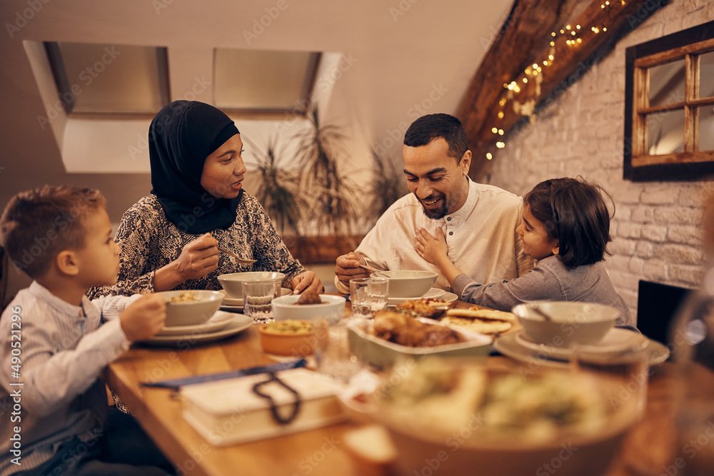 Wall mural Happy Muslim family has fun during evening meal at home on Ramadan.