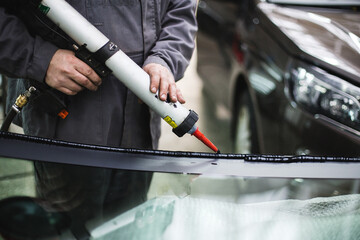 auto repairman sealing car windshield