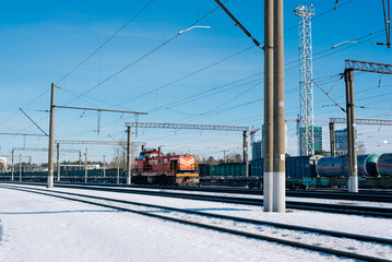 Obraz premium Overhead railway power lines and holding structures under blue sky and train